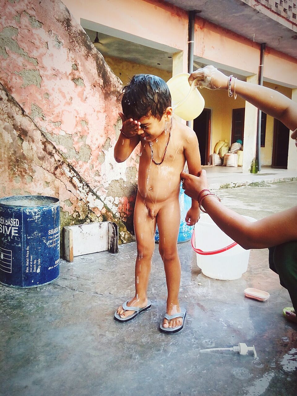 Mother bathing son outside house