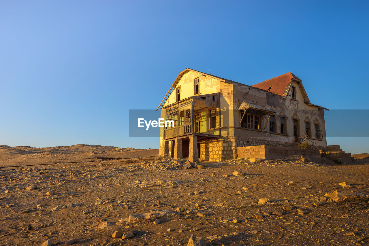 LOW ANGLE VIEW OF OLD ABANDONED BUILDING AGAINST CLEAR BLUE SKY