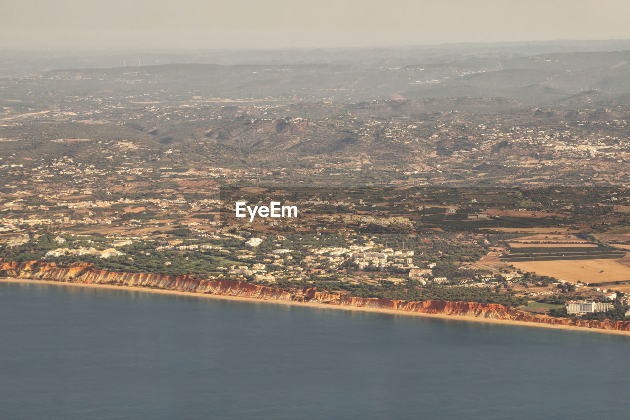 Aerial view of city by sea against sky