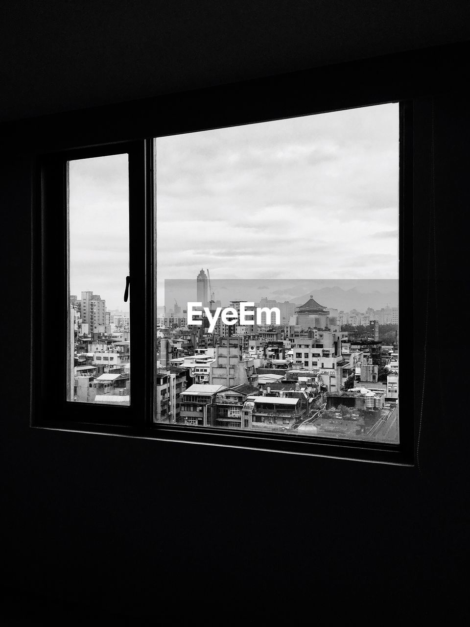 View of cityscape and cloudy sky seen through glass window