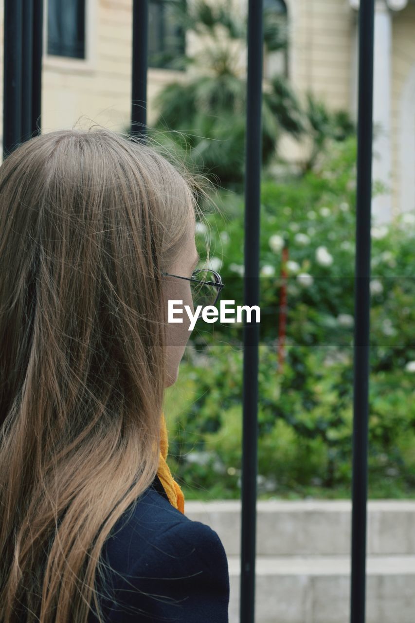 Side view of woman looking through gate