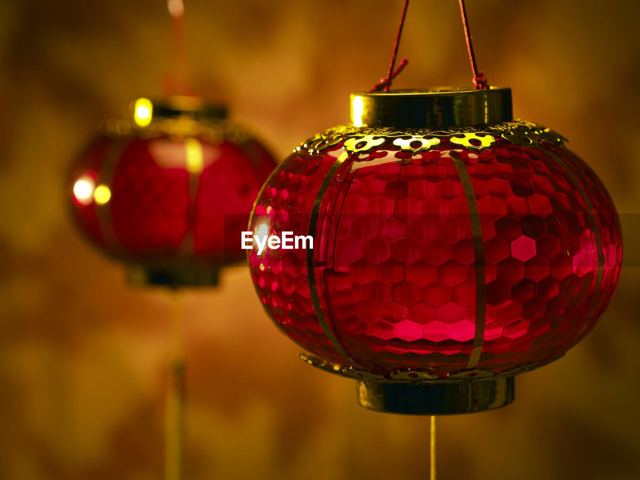 Close-up of illuminated lanterns hanging against wall