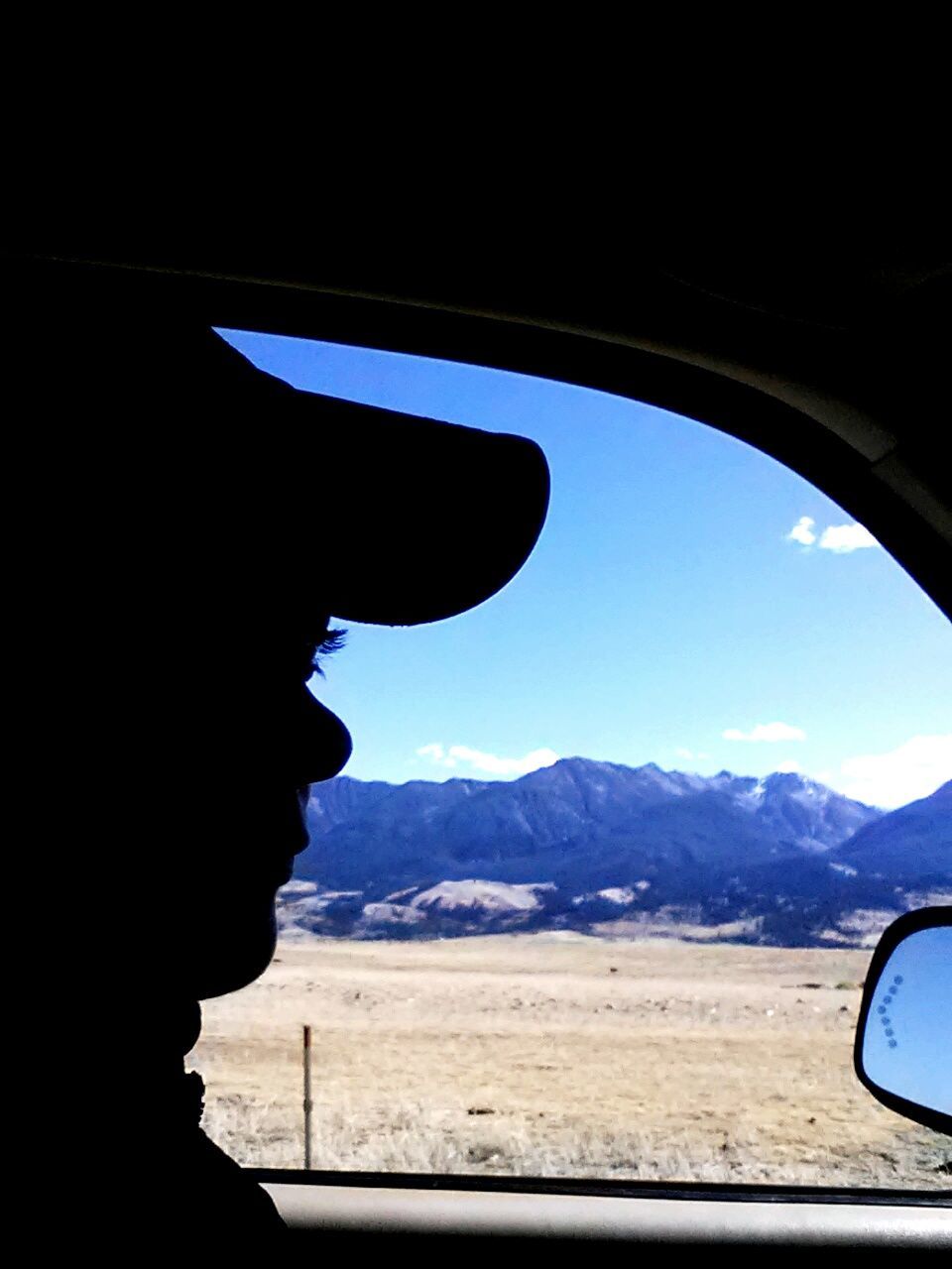 Close-up of silhouette person driving car against mountains