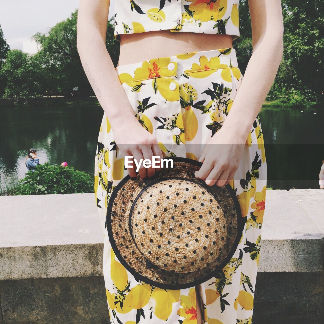 Mid section of a woman holding hat