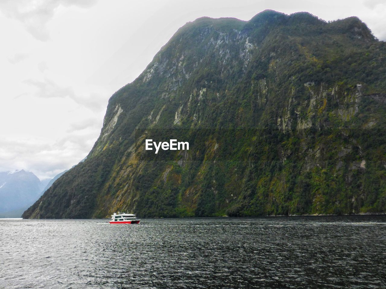 Boat sailing on sea against mountains