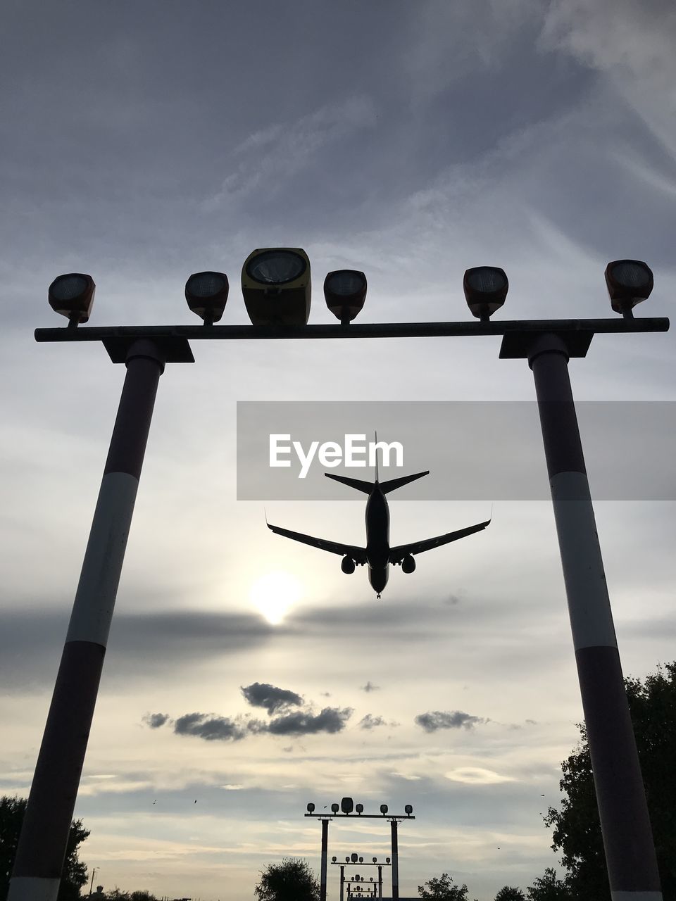 Low angle view of silhouette airplane flying against sky during sunset