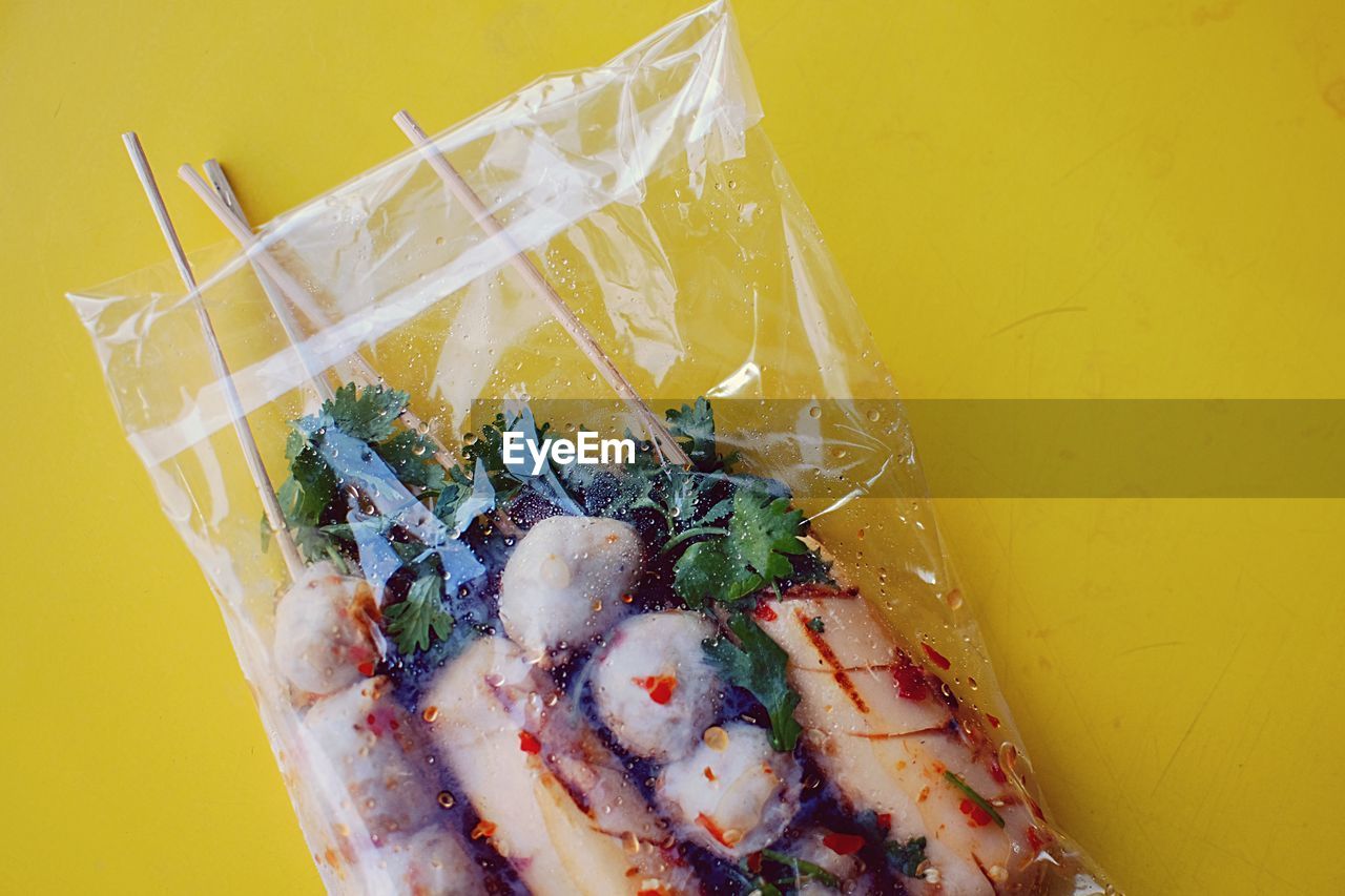 High angle view of food in plastic packet against yellow background