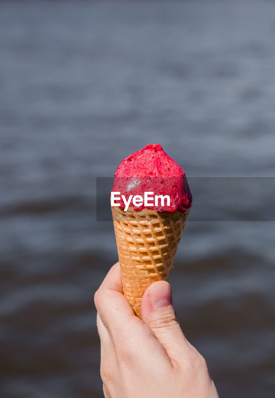 CLOSE-UP OF HAND HOLDING ICE CREAM