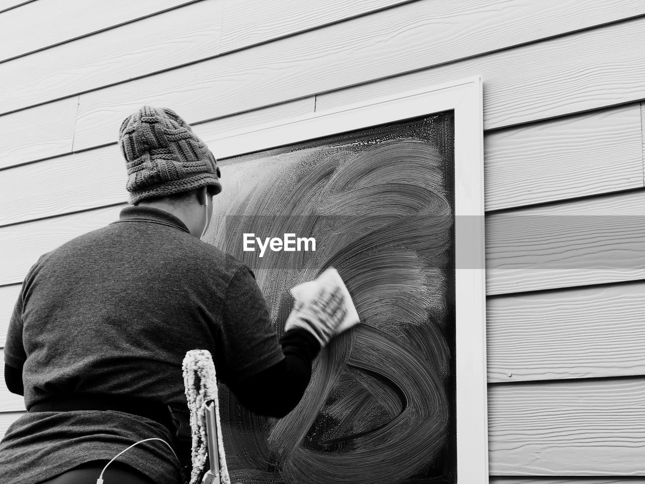 Rear view of woman cleaning window