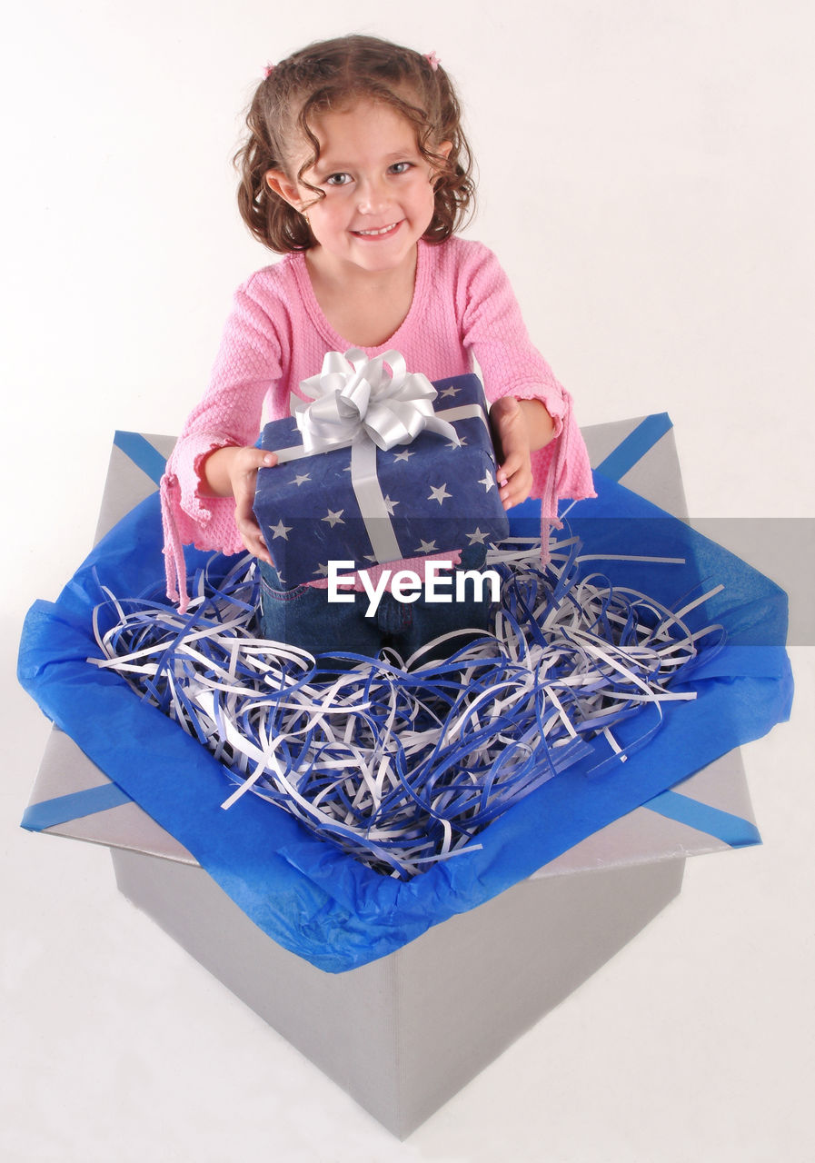 Portrait of girl with gift in box against white background