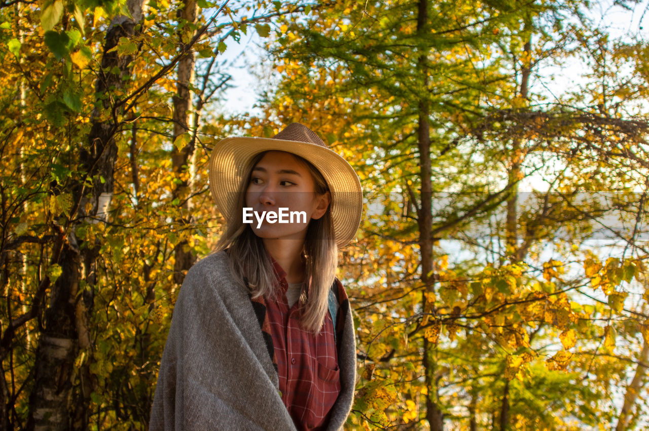 Portrait of beautiful young woman in forest during autumn