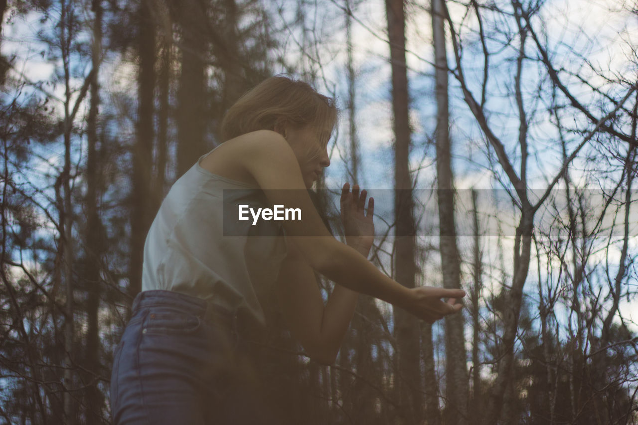 Low angle view of young woman dancing in forest