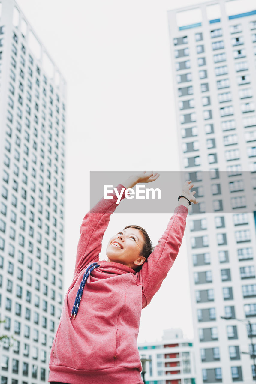 Low angle view of girl against building in city