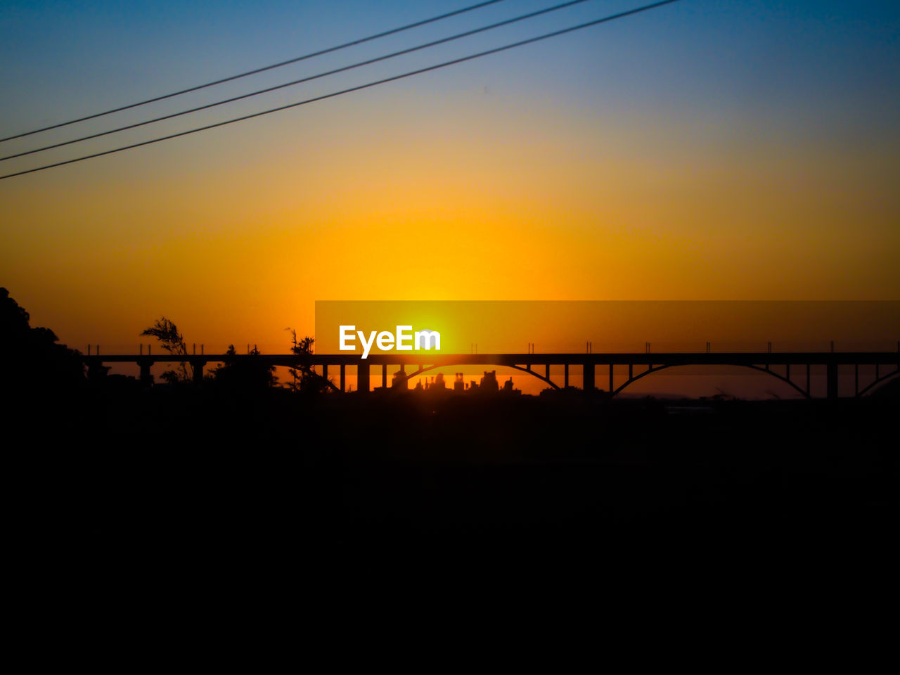 Silhouette of bridge and trees against sky during sunset