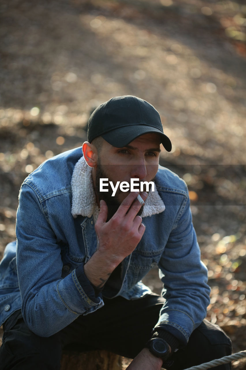 YOUNG MAN LOOKING DOWN WHILE SITTING ON CAMERA