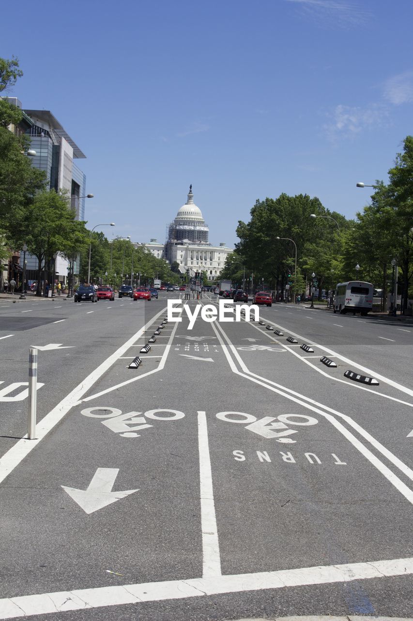 Road leading towards capitol building against sky on sunny day