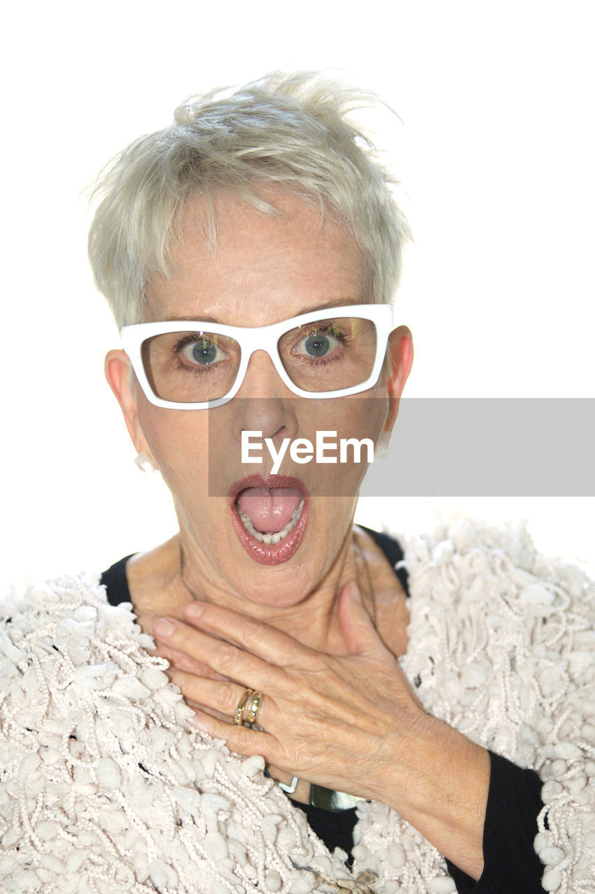 Portrait of senior woman with shocked expression against white background