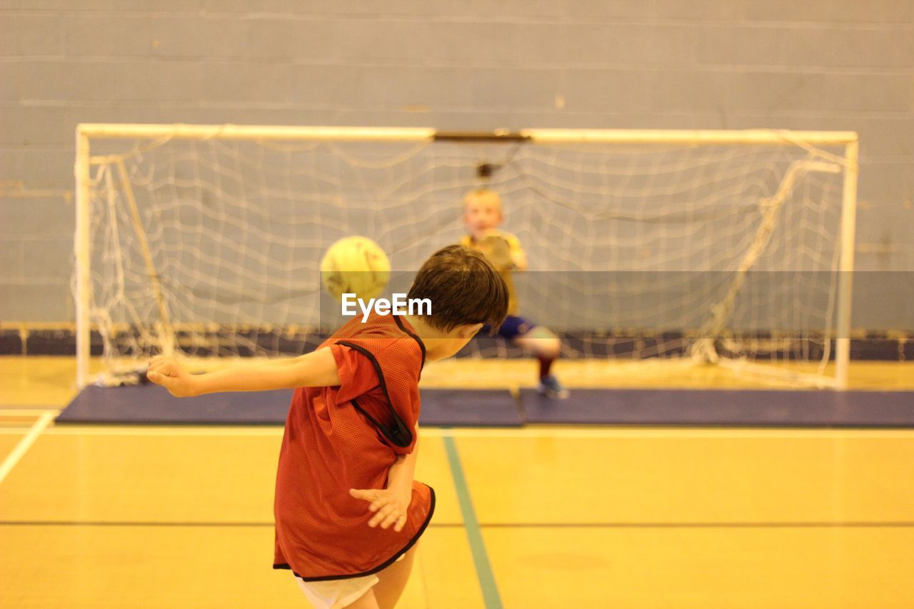 REAR VIEW OF MAN PLAYING WITH BASKETBALL IN COURT