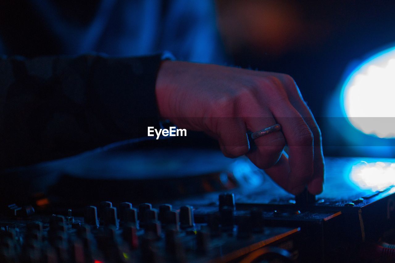 Cropped hand of male dj playing music at nightclub
