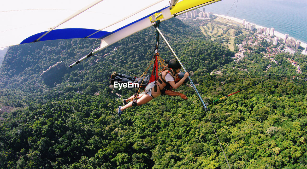 Man and woman hang gliding over mountain