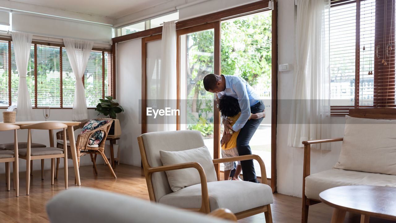 Boy embracing father on doorway at home