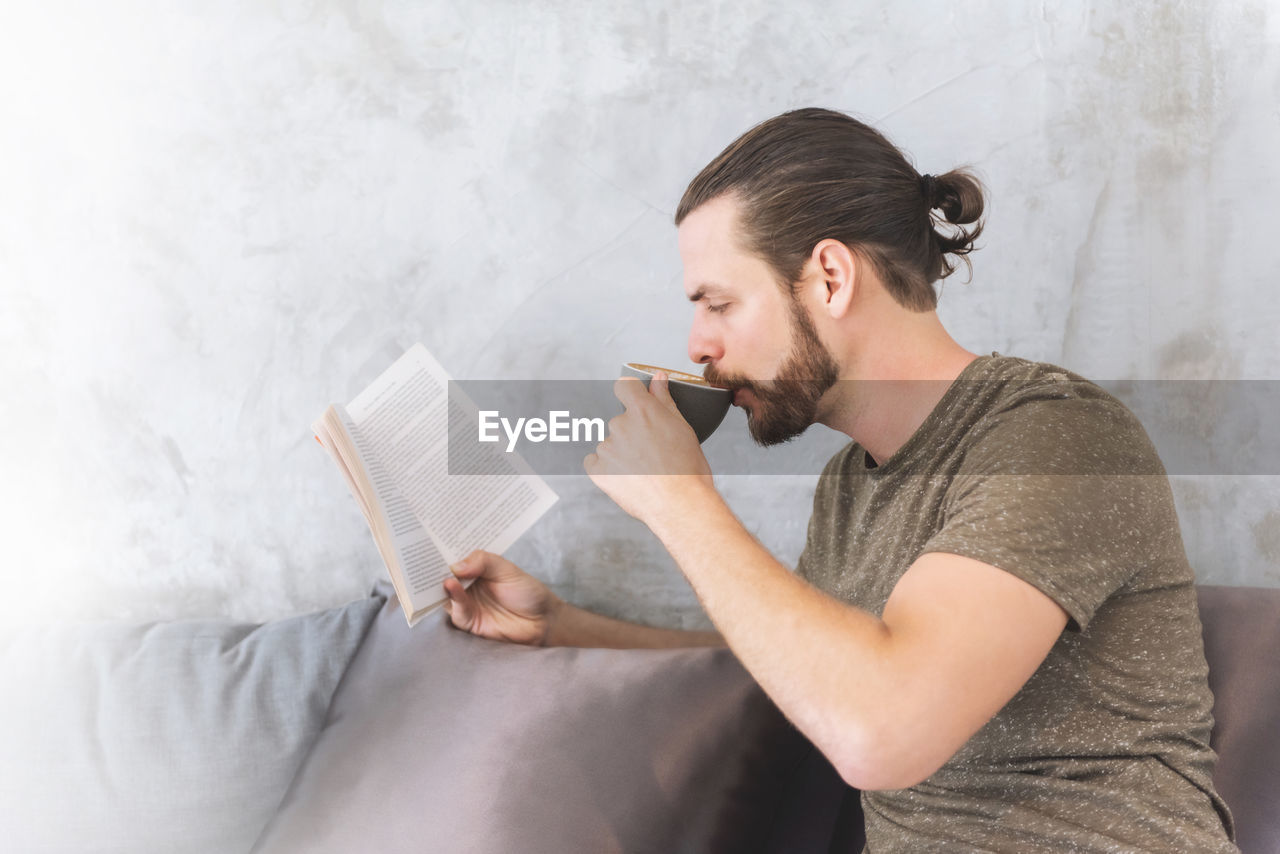 Man having coffee while reading book