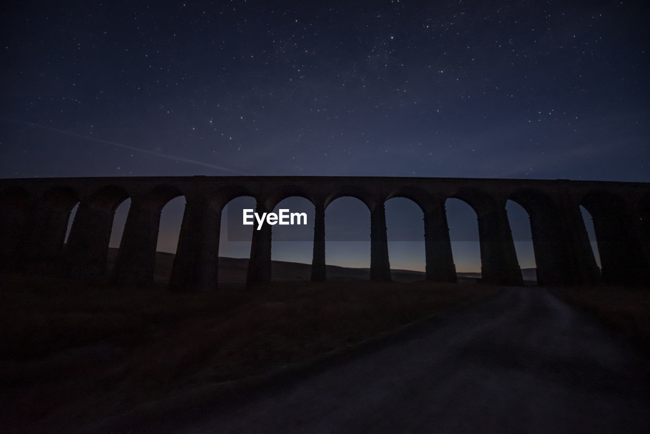 Low angle view of arch bridge against sky at night