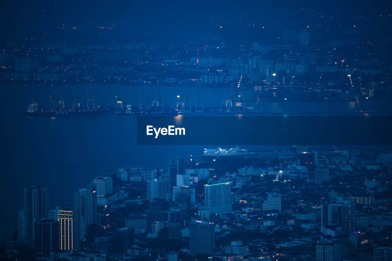 Aerial view of cityscape by bay at night