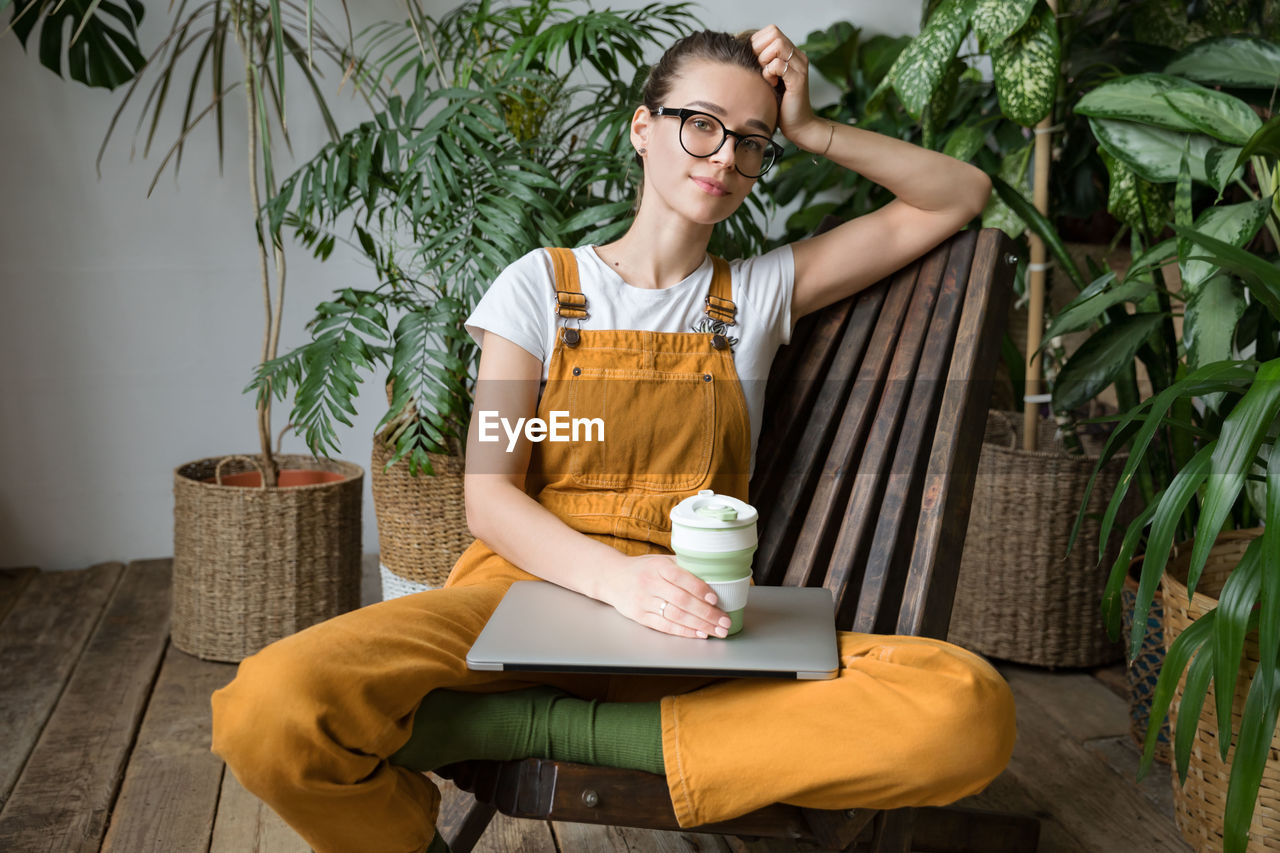 Portrait of woman with laptop sitting at home