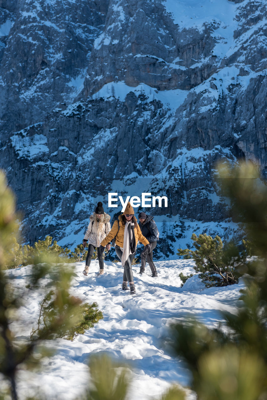 Group of friends hiking on snowy path in mountains