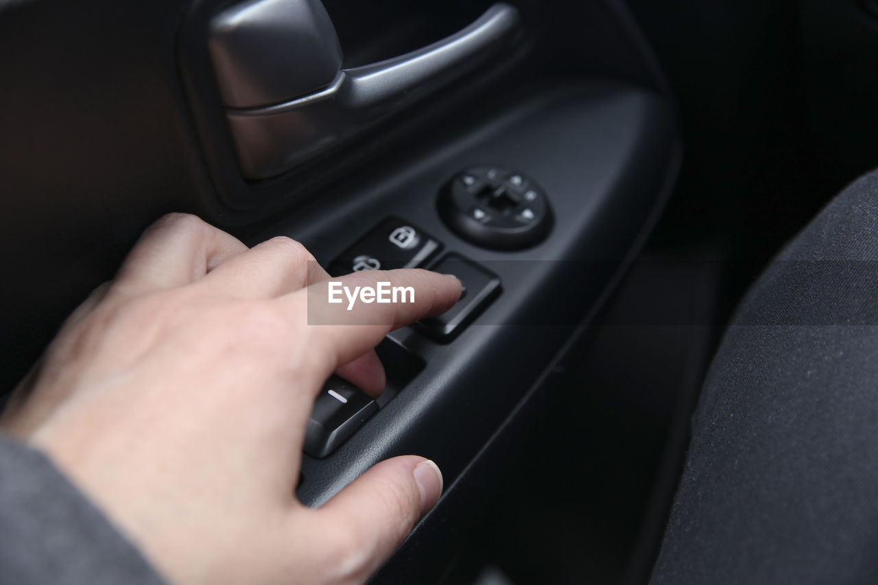 Cropped image of person touching push button in car