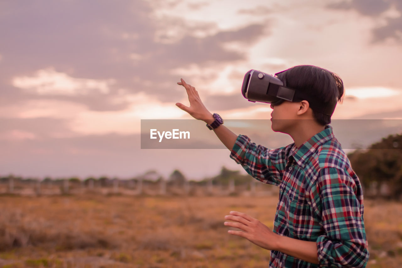 Man in tartan shirt wearing virtual reality headset reality in beautiful sky