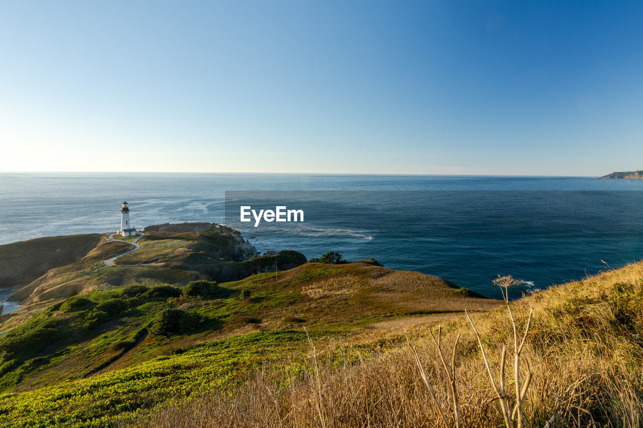 Scenic view of yaquina head lighthouse in newport, oregon, usa, against blue sky