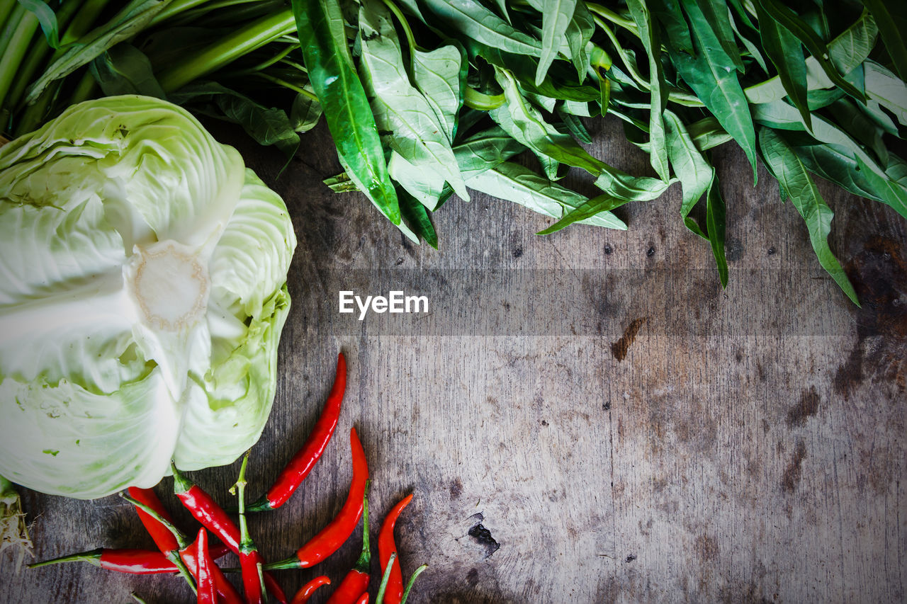 Directly above shot of leaf vegetable with cabbage and chili peppers on wooden table