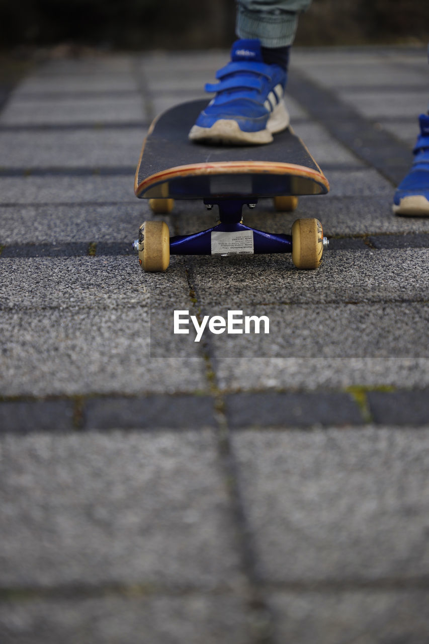 LOW SECTION OF CHILD SKATEBOARDING ON SKATEBOARD