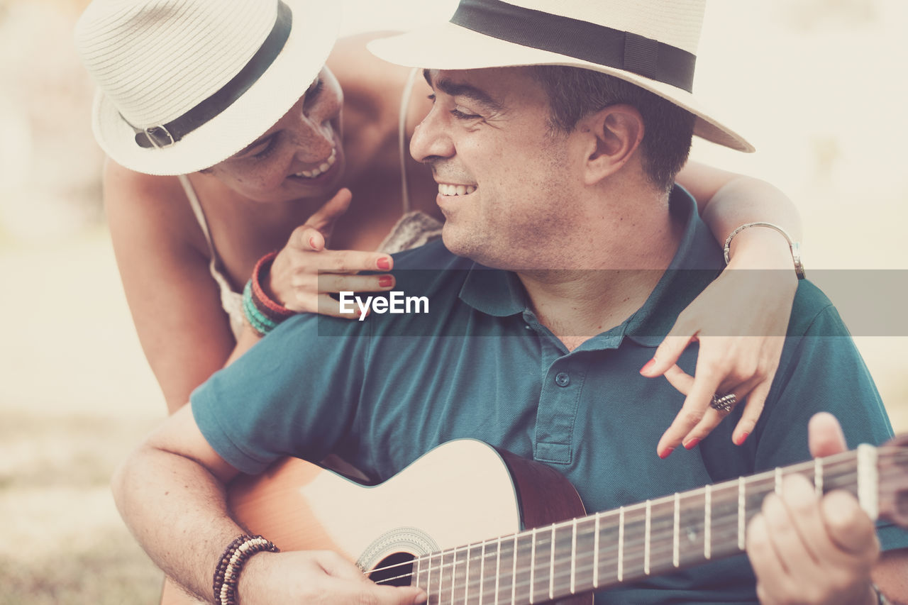 Happy woman listening to man playing guitar