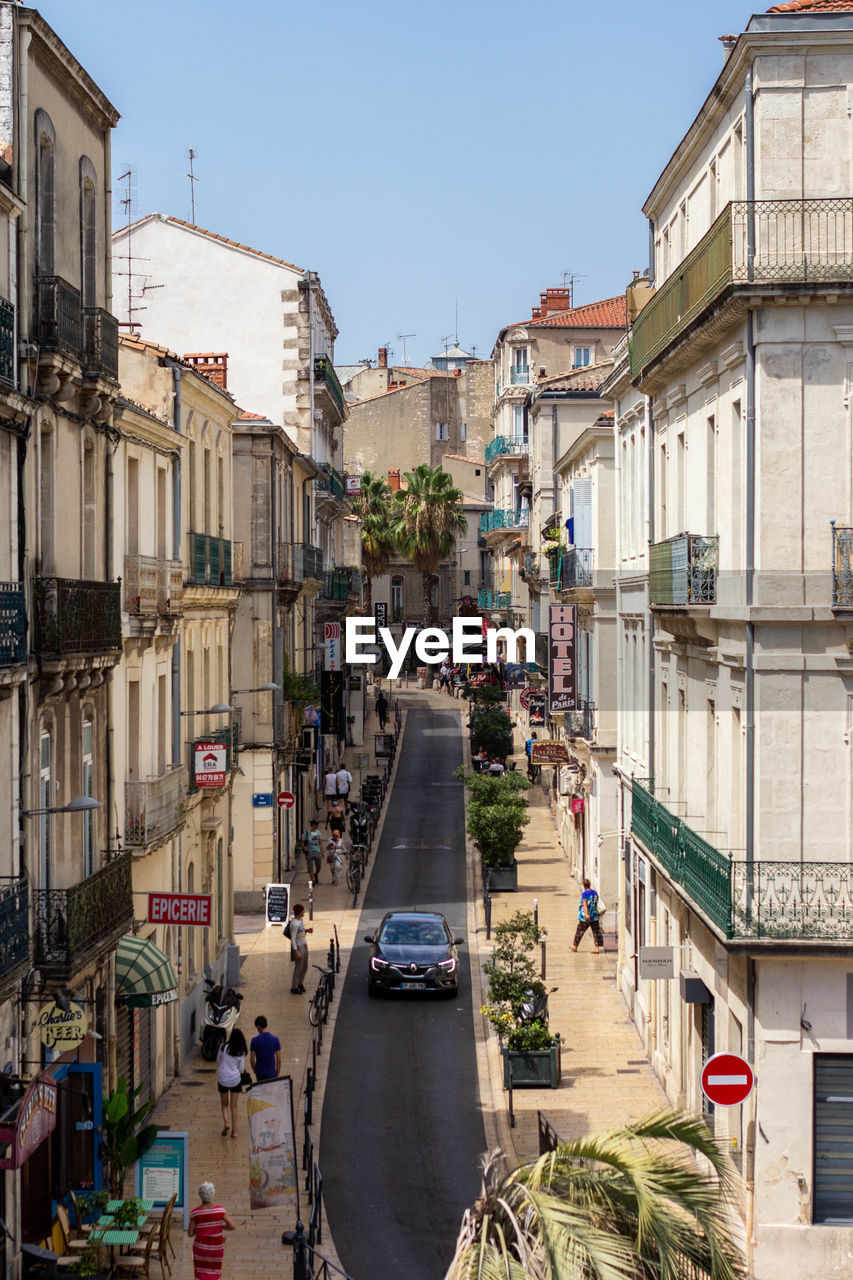 VEHICLES ON ROAD AMIDST BUILDINGS AGAINST SKY