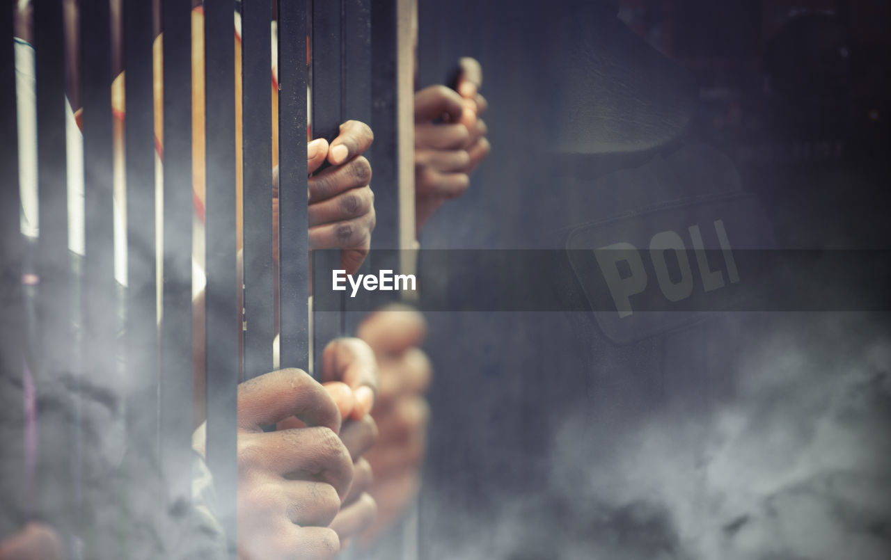 Close-up of prisoner standing behind prison bars