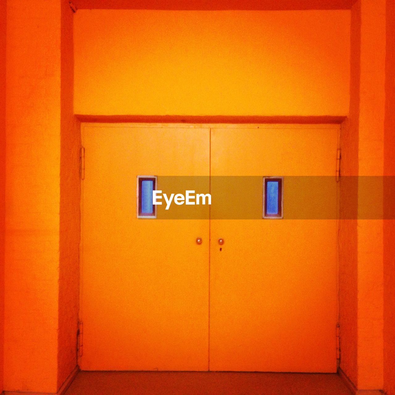 Close-up of orange wall with closed doors