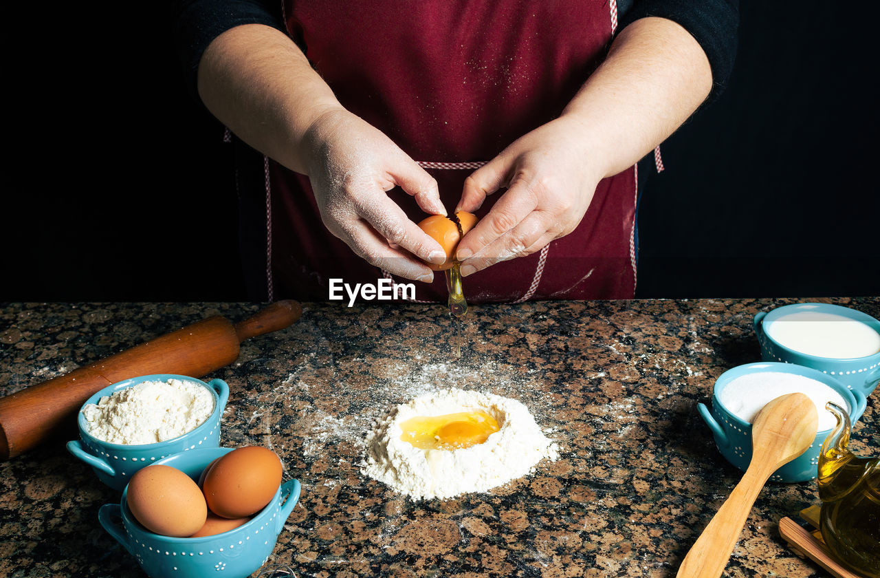 HIGH ANGLE VIEW OF PERSON PREPARING FOOD ON TABLE