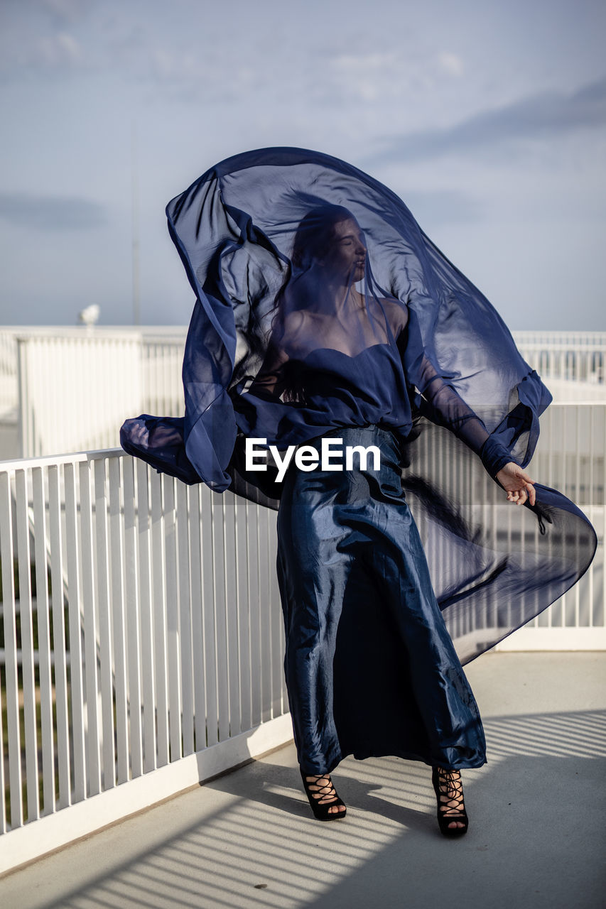 Full length of woman wearing navy blue dress while standing by railing