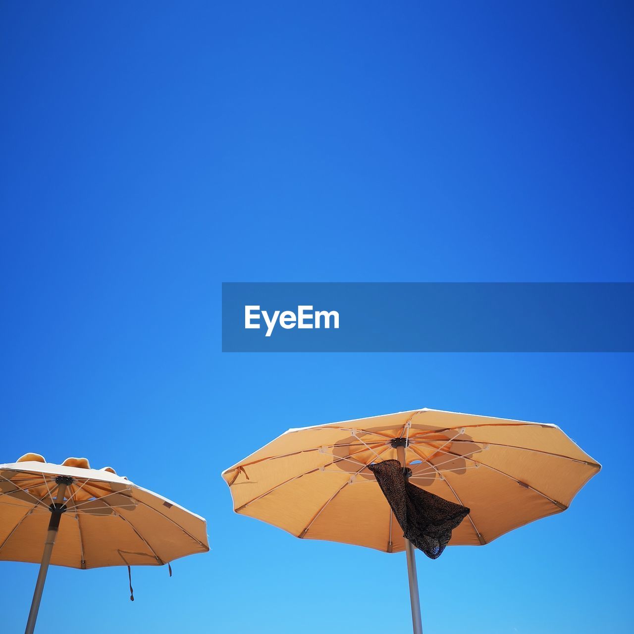 Low angle view of umbrella against clear blue sky