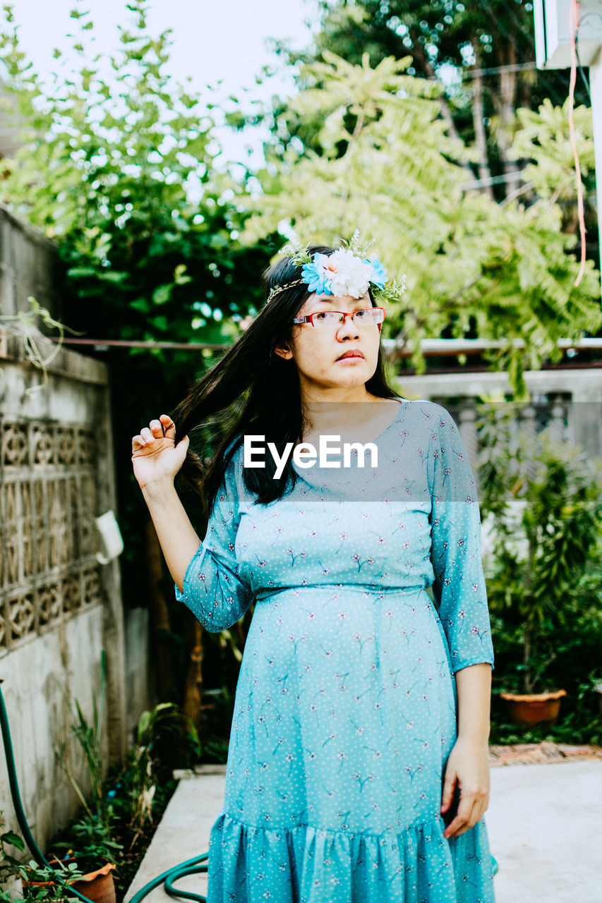 Young woman looking away while standing against plants