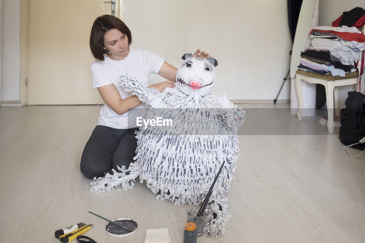 Woman making stuffed toy sitting at home