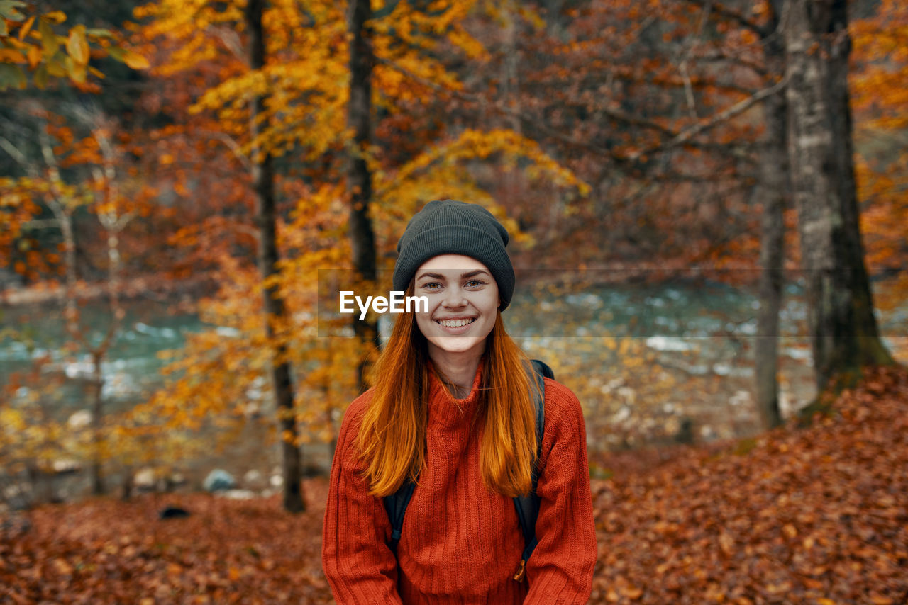 PORTRAIT OF A SMILING YOUNG WOMAN IN AUTUMN