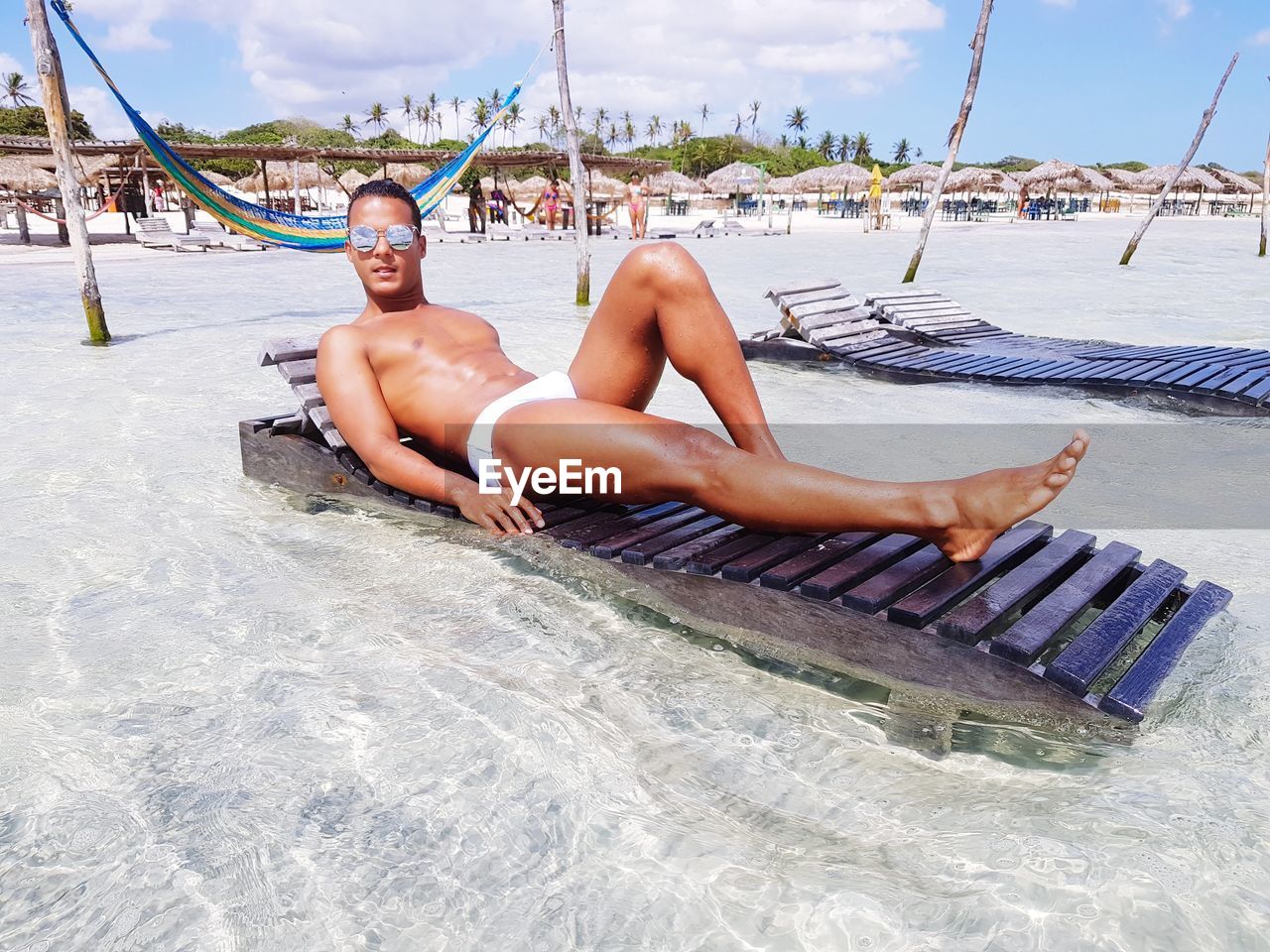 Young man lying on lounge chair at beach