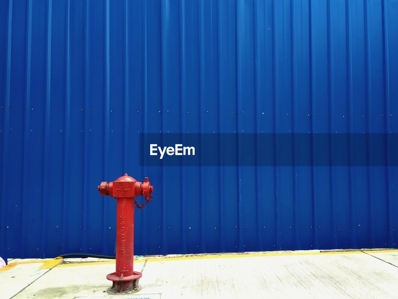 Close-up of fire hydrant on footpath against blue wall