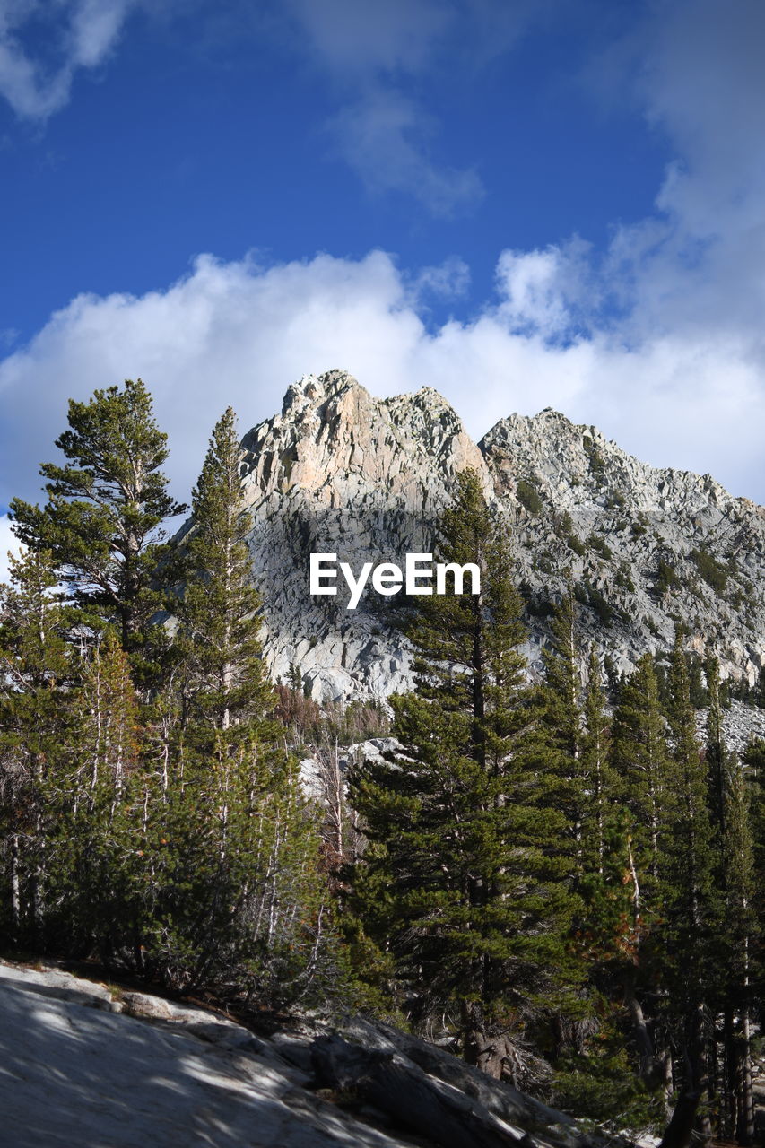 reflection, sky, nature, cloud, tree, plant, low angle view, rock, mountain, beauty in nature, no people, sunlight, scenics - nature, day, blue, outdoors, land, water, environment, travel, tranquility, travel destinations, pinaceae, cliff, coniferous tree, terrain, pine tree, architecture, landscape