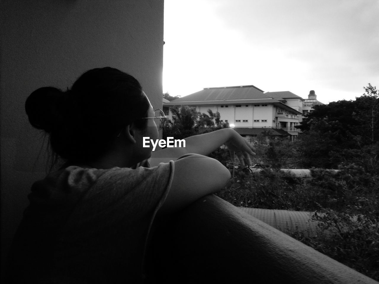 SIDE VIEW OF YOUNG WOMAN SITTING OUTSIDE HOUSE