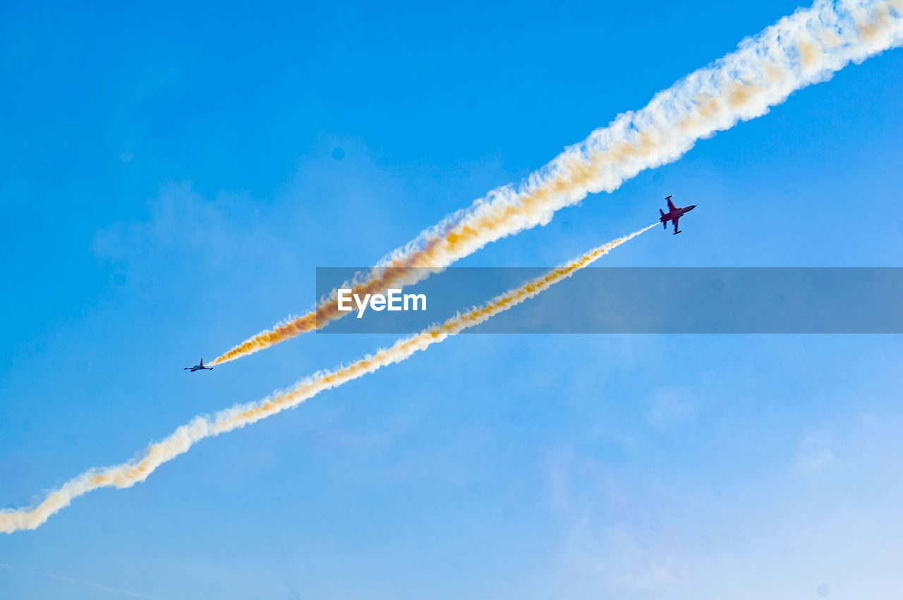 Low angle view of airplane flying against blue sky